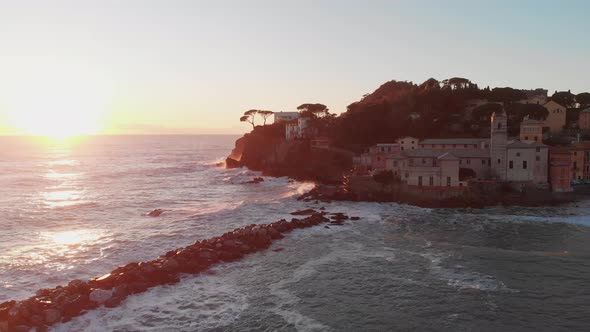 Aerial of Baia del silenzio, Sestri Levante, Italy. Ancient church by the sea at sunset. The waves h