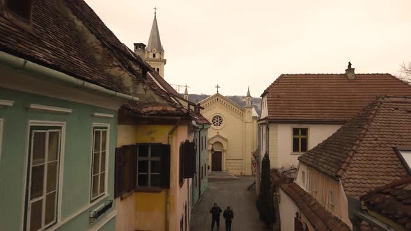 A dolly movement drone shot, amidst a vintage architechtural lane in a closed locality, with a churc