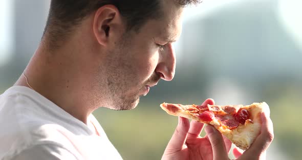 Handsome man eating pizza outdoor.