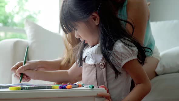 An Asian mother Teaching Her Daughter to Draw 