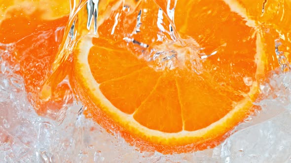 Super Slow Motion Shot of Pouring Water on Tangerine Slices and Ice Cubes in Glass at 1000 Fps