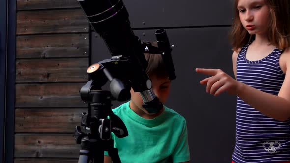 Cute Girl and Her Little Brother are Studying Sky Through a Telescope