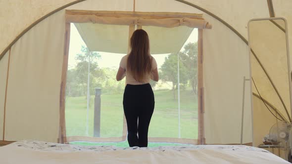 Back View of Female Tourist on Vacation in Modern Tent with Bed