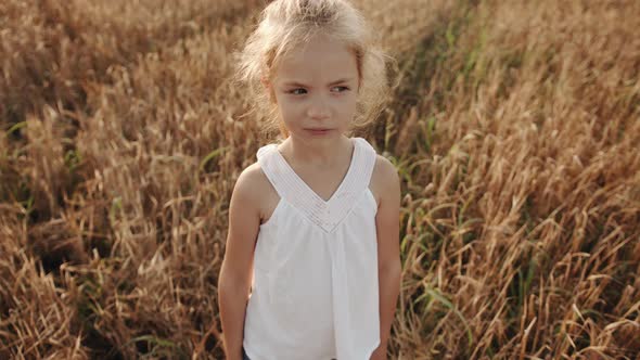 Portrait of a Cute Longhaired Blonde Preschool Girl in a White Tunic in a Wheat Field