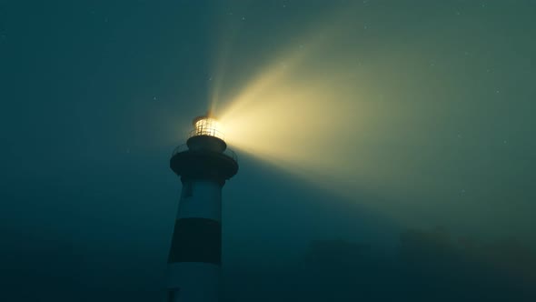 Lighthouse light spinning around. Tall tower standing on the coastline.
