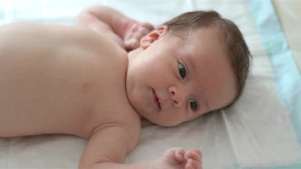 Naked baby is lying on white blanket