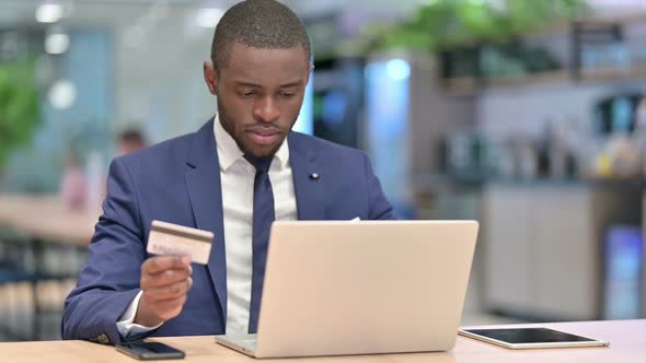 Online Payment Success on Laptop for African Businessman in Office