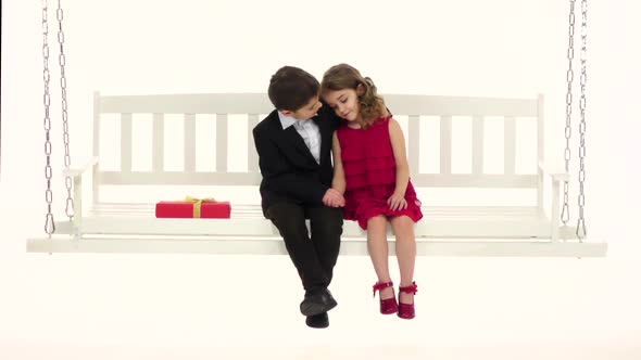 Little Boy Straightens His Hair To His Girlfriend and Embraces Her Trembling. White Background. Slow