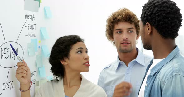 Attractive young creative designer talking to her colleagues