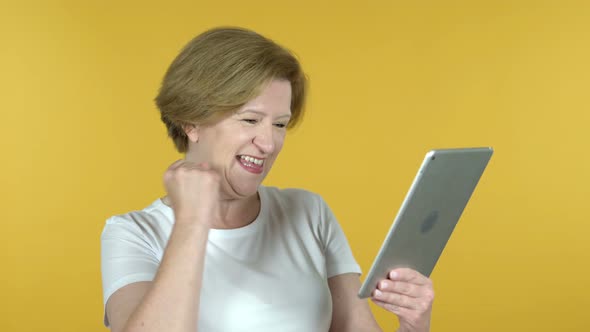 Old Woman Excited for Success While Using Tablet Isolated on Yellow Background