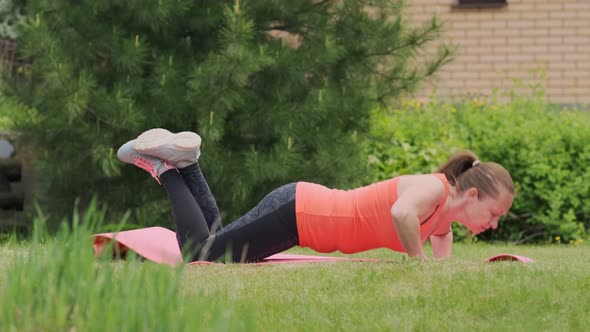 woman is engaged in fitness outdoors by doing physical exercises on mat