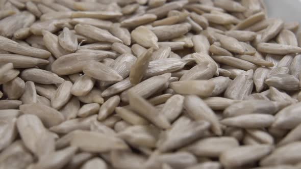 Peeled raw sunflower seeds fall into the heap with rotation