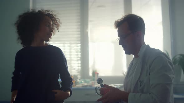 Serious Doctor Listening Breathing Preteen Patient Using Stethoscope in Clinic