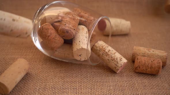 Wine corks fall on burlap against a background of wineglass. Slow motion.