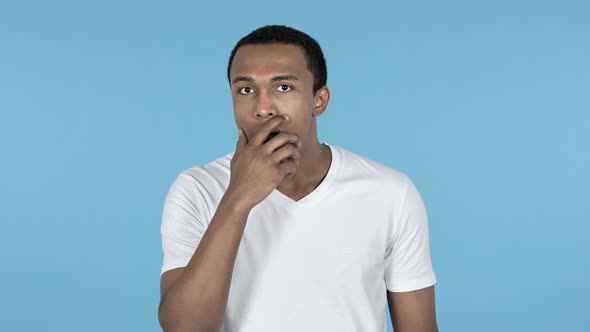 Shocked Surprised Young African Man Standing, Blue Background in Wonder