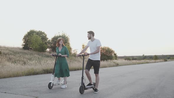 Couple Enjoying and Having Talk Together During a Walk with Electric Scooters