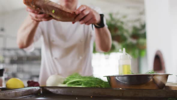 Caucasian female chef preparing a dish and smiling in a kitchen