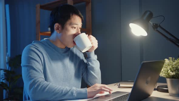 Asia businessman take a break with a cup of coffee relax and checking work assignment at laptop.