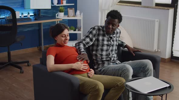 Married Interracial Couple Expecting Baby Sitting on Couch