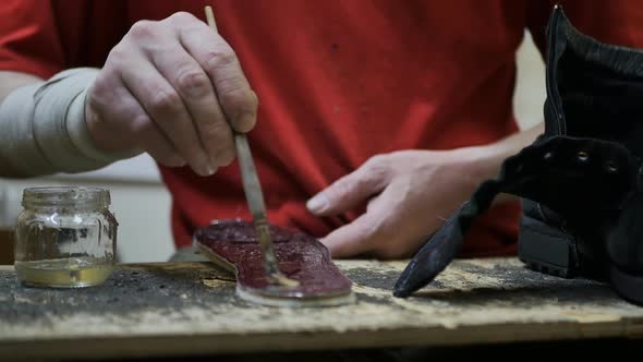 Shoemaker's Hands Applying Glue to the Insole of a Shoe with a Brush