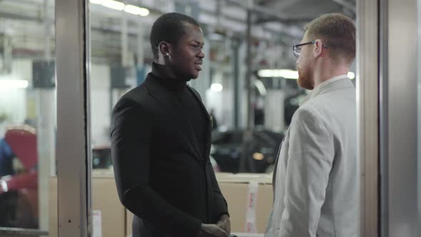 Portrait of Successful Male African American Car Dealer Giving Keys To the Buyer