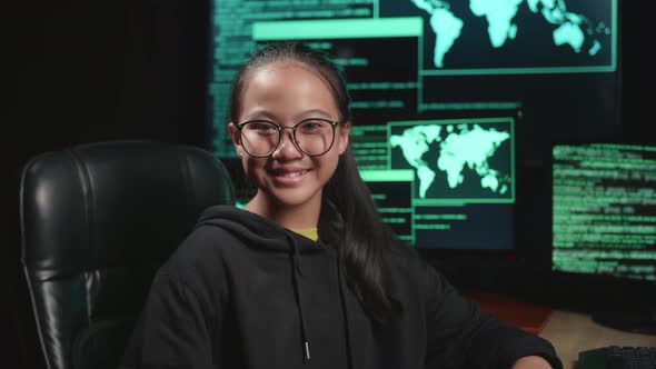 Asian Young Girl Hacker Hacking With Multiple Computer Screens And Smiling To Camera In Dark Room