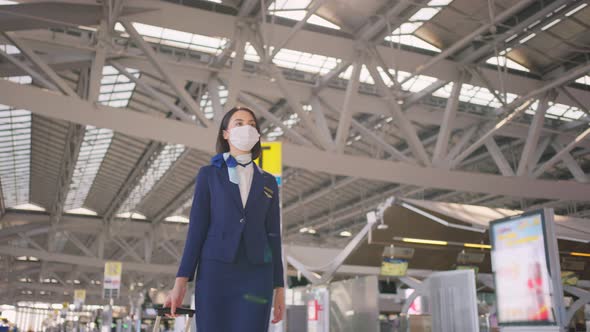 Cabin crew or air hostess wearing face mask walking in airport terminal to the airplane due to Covid