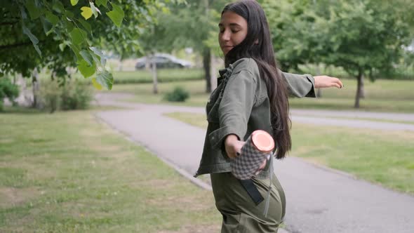 Cheerful Hipster Girl Dancing in the Park To the Music Using a Portable Acoustic Speaker