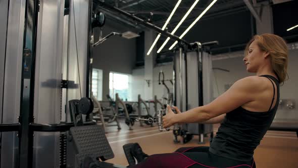The Girl Does Exercises at Exercise Machine for the Muscles of the Biceps