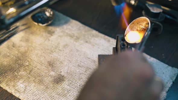 Jeweler Pours Molten Metal Into Form on Table Close View