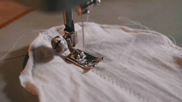 Sewing Machine Needle in Slow Motion. A Tailor Sews Homemade Face Mask of Fabric