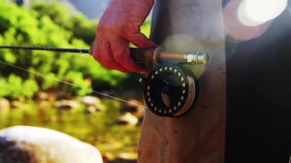 Fly fisherman standing in rock with fishing rod