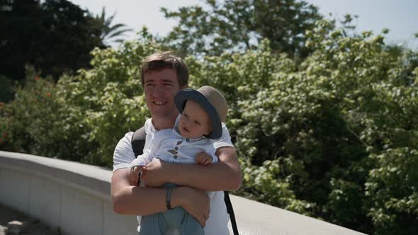 Man Holds Toddler Boy in Arms Standing on Observation Deck