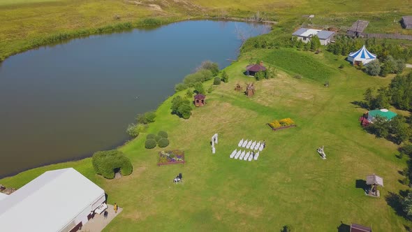 Green Field with Wedding Decorations at Lake Aerial View