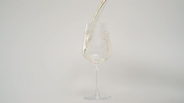 Slow Motion of Pouring White Wine in Tilted Glass White Background