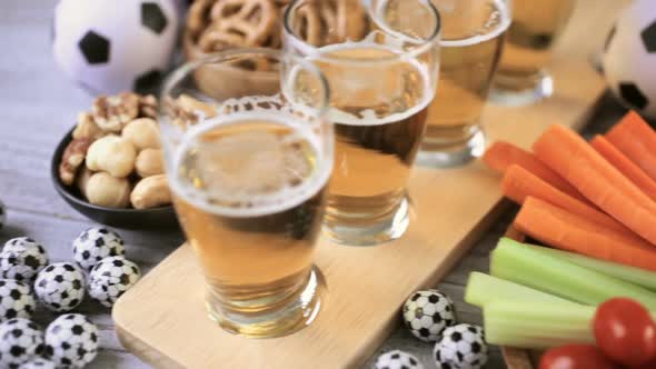 Draft beer and salty snacks on the table for soccer party.