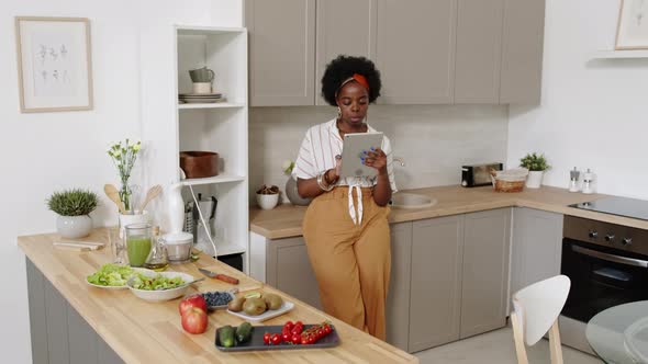 African American Woman with Digital Tablet at Kitchen