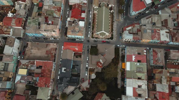 Aerial top down dolly in of charming red rooftops houses and cars driving in Valparaiso city, Chile