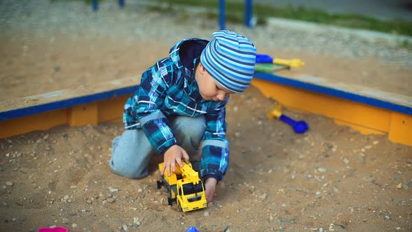 Child Playing in the Sandbox with Toy Machine