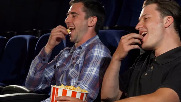 Male Friends Eating Popcorn and Laughing While Watching Comedies at the Cinema