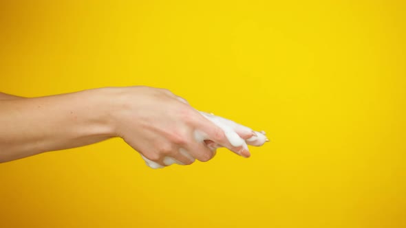 Washing Female Hands on Yellow Background Using Liquid Soap or Foam