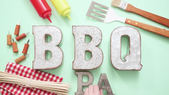 Metal BBQ Party sign with grilling tools on blue background.
