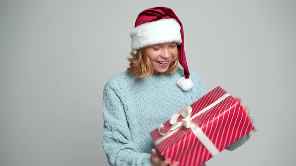 Happy Young Girl in Santa Claus Cap Holding Present