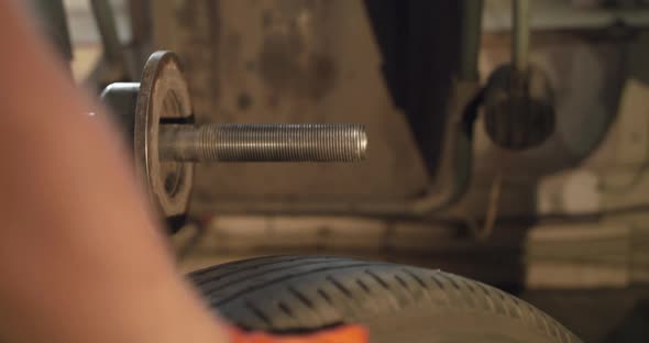 Mechanic Putting the Wheel on a Machine Tool for Balancing Tire in Auto Service