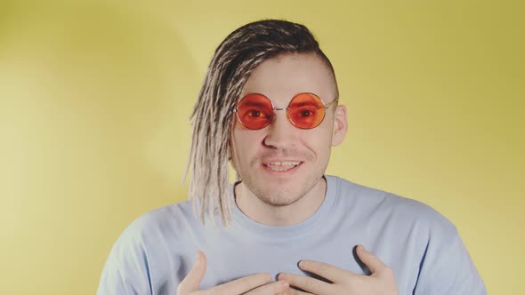 Young handsome happy man in bright sunglasses surprised asking, pointing at yourself.