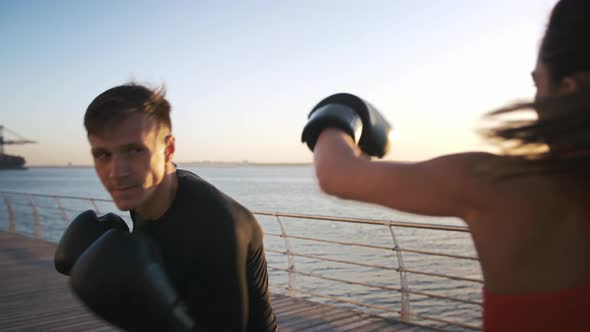 Young Female in Boxing Gloves is Boxing with Her Skillful Instructor