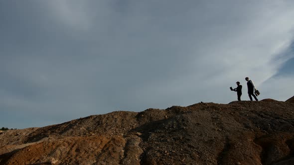 Two Businessmen Silhouettes Walk on Top of a Hill