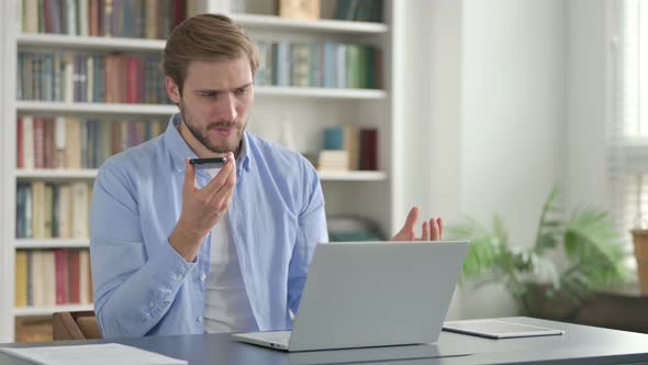 Man Feeling Angry on Smartphone While Using Laptop