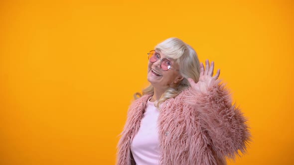 Childish Elderly Woman in Pink Coat and Round Sunglasses Making Faces for Fun