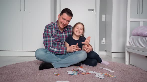 Father and daughter. They look at the camera and speak to the camera. Then they hug